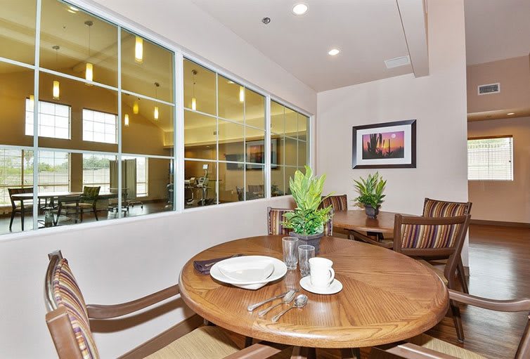 A cozy dining area with a wooden table and chairs, adorned with plants and art on the wall.