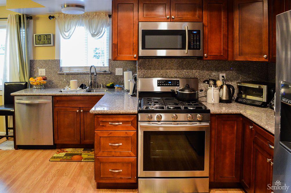 A modern kitchen with wooden cabinets, featuring a stainless steel oven and microwave.