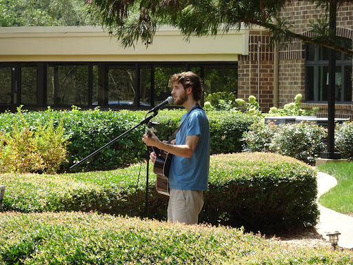 A musician performing outdoors with a guitar on a sunny day.