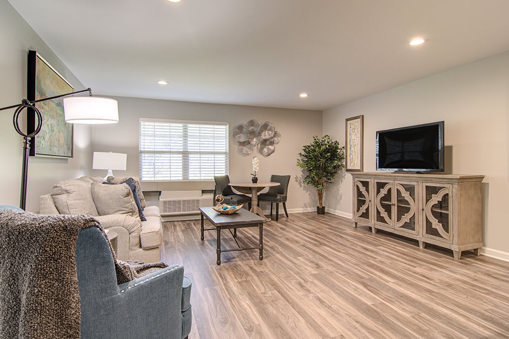 A modern living room with cozy seating, wood flooring, and a small dining area.