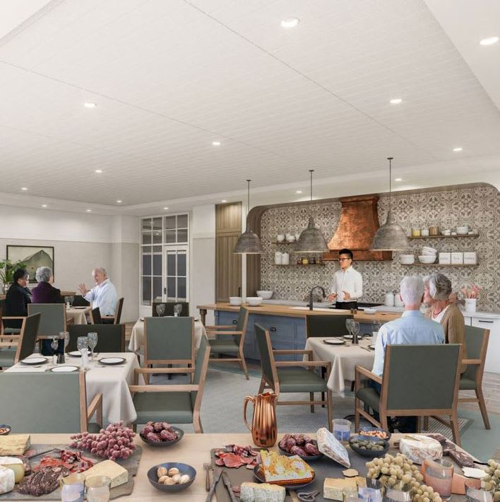 A modern restaurant interior with a dining area and buffet setup, featuring guests enjoying their meals and a chef preparing food in an open kitchen.