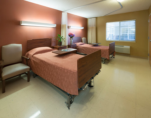 A well-lit hospital room featuring two beds, designed for patient comfort.