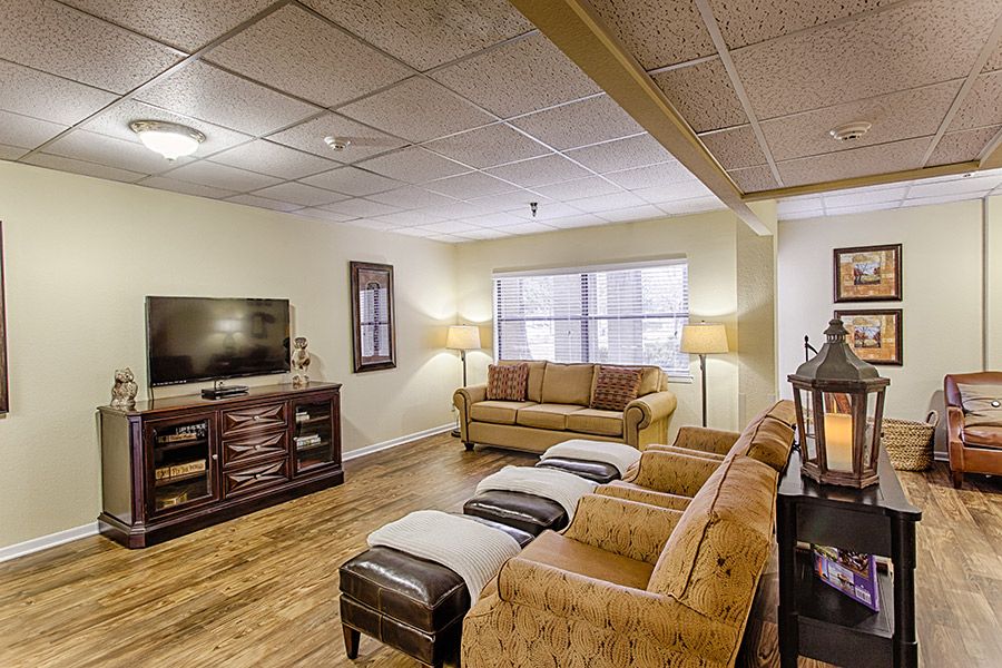 A cozy living room featuring comfortable sofas, a television on a wooden stand, and warm lighting from lamps.