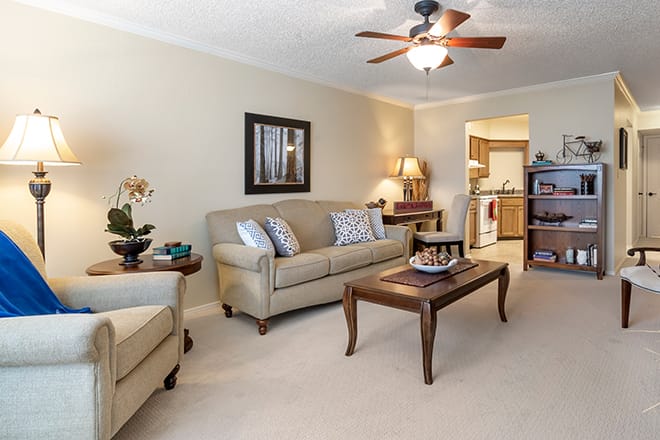 A cozy living room with a sofa, coffee table, and ceiling fan.