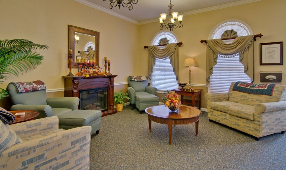 A cozy living room with elegant furnishings, featuring a fireplace and chandelier.