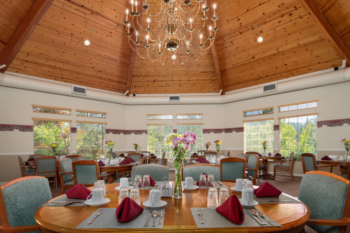 An elegant dining room with beautifully set tables and a grand chandelier overhead.