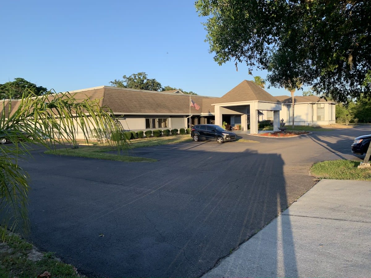A building with an entrance surrounded by a driveway and trees under clear blue sky.