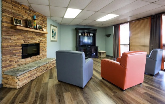 A cozy living room with modern decor, featuring colorful chairs and a stone fireplace.
