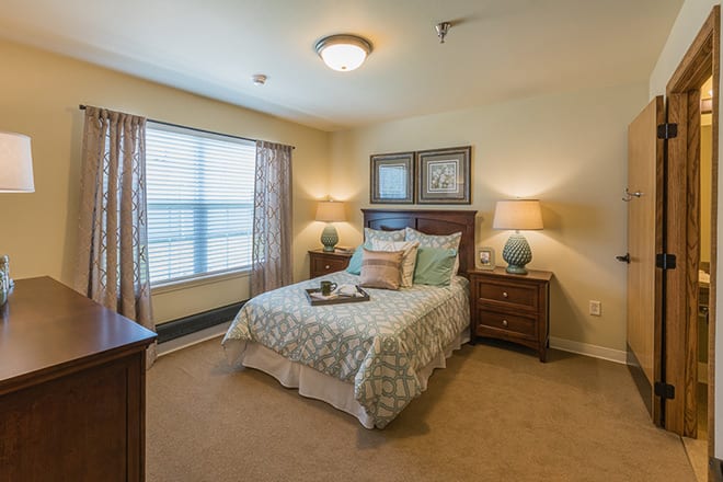 Cozy bedroom with a neatly made bed, bedside tables, and natural light.