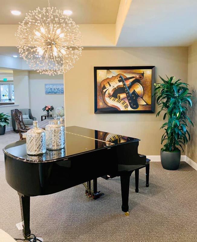A stylish living room featuring a grand piano, elegant chandelier, and framed artwork.