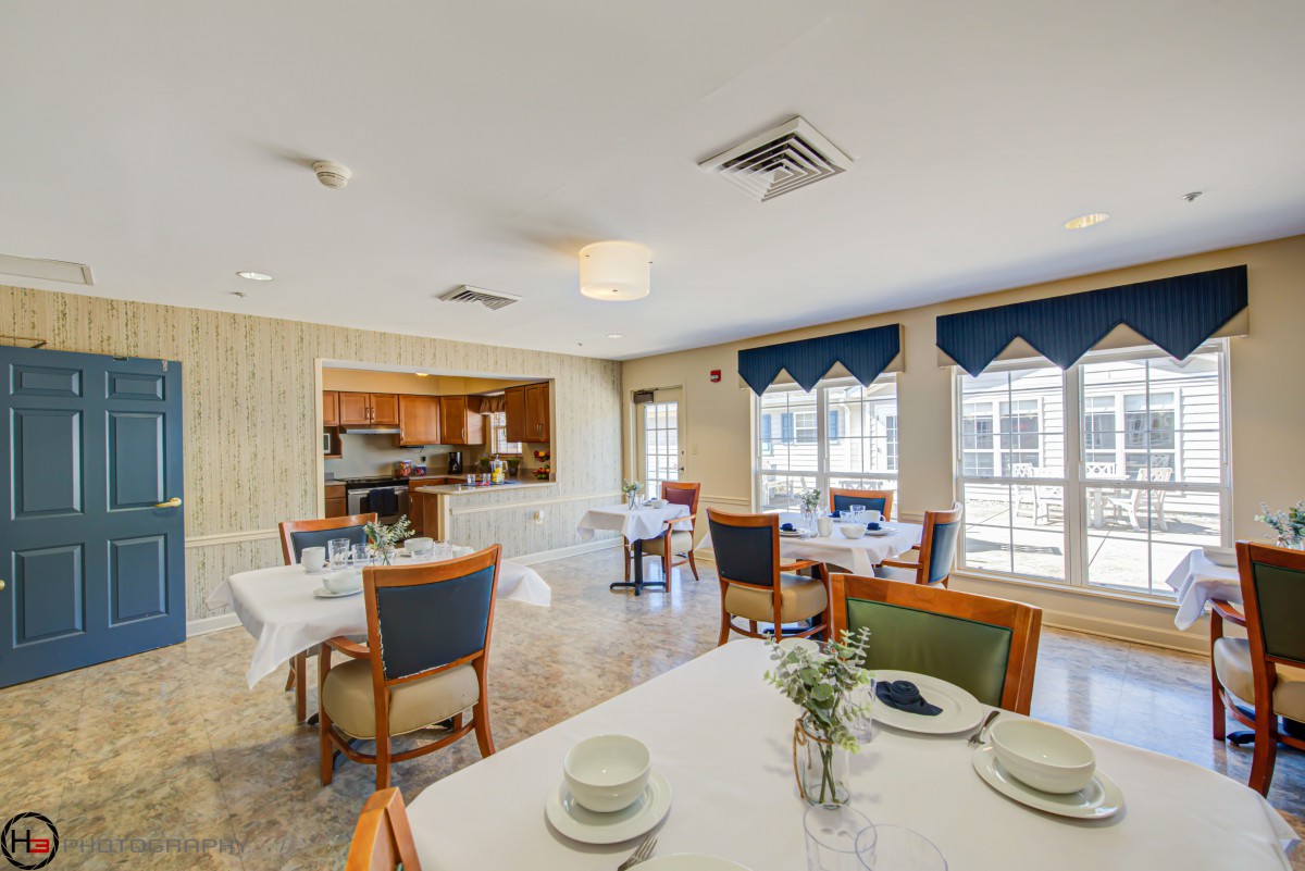 A bright and inviting dining area with neatly set tables, chairs, and large windows letting in natural light.