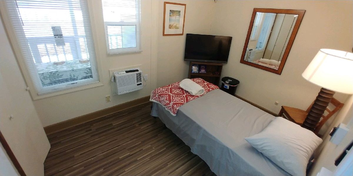 A cozy, small bedroom with a single bed and TV.