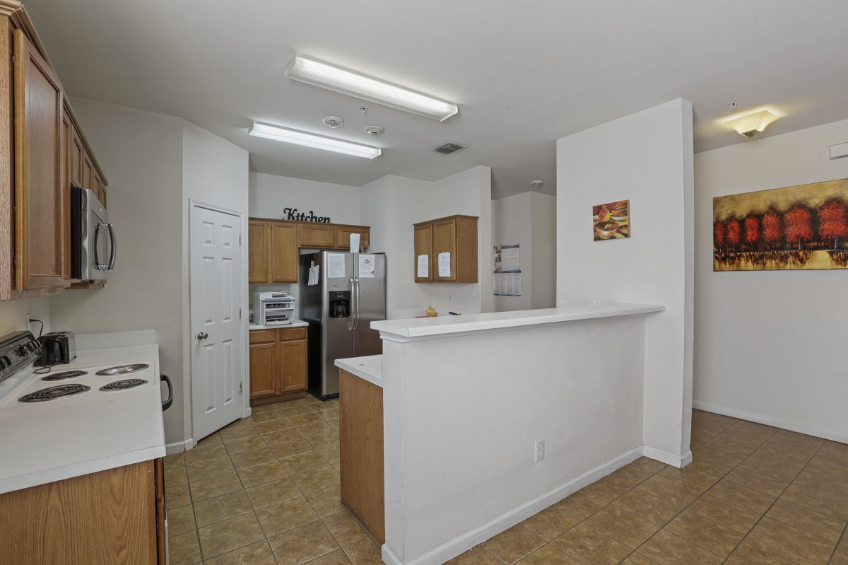 A modern kitchen with wooden cabinets, stainless steel appliances, and a white countertop.