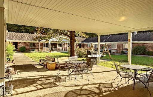 A serene outdoor patio area with seating, surrounded by greenery.