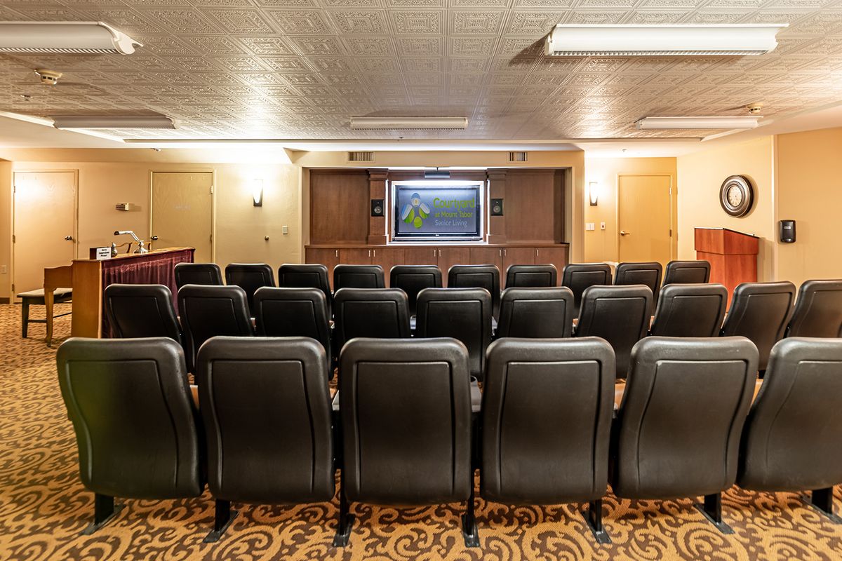 A cozy home theater with rows of comfortable seating facing a large television screen.