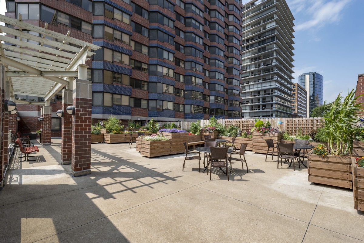 A spacious rooftop terrace with seating, surrounded by urban buildings.