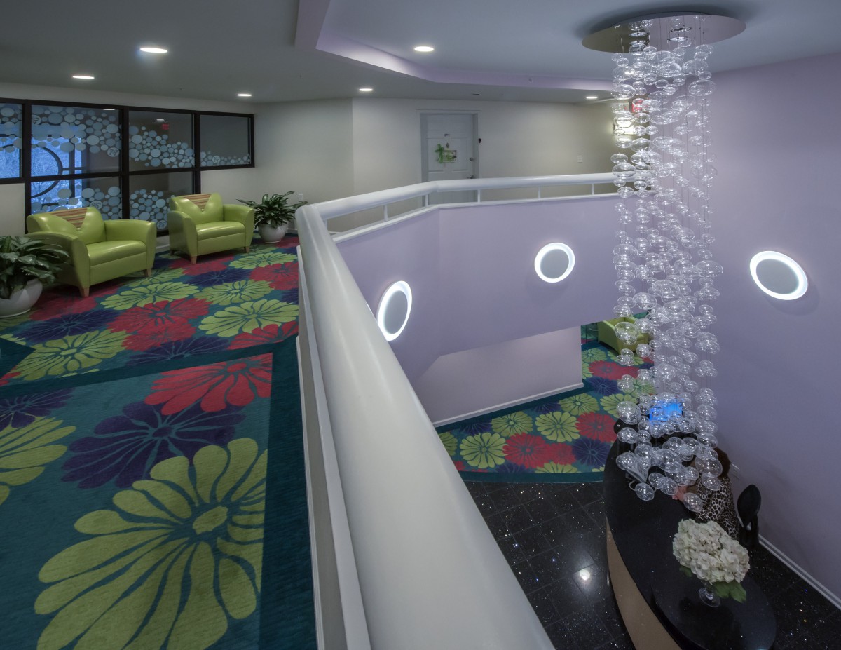 A modern lobby interior with colorful carpeting, comfortable seating, and decorative lighting.