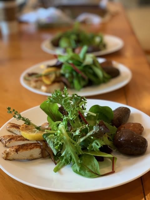 A beautifully plated meal featuring grilled chicken, a fresh green salad, and roasted potatoes.