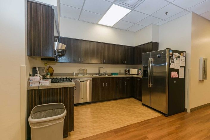 A modern kitchen with dark cabinets and stainless steel appliances.