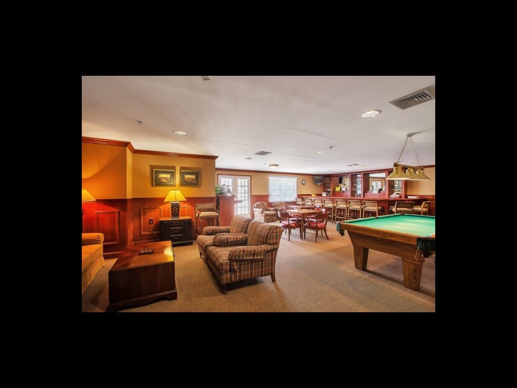A cozy living room with a pool table, wood paneling, and comfortable seating.