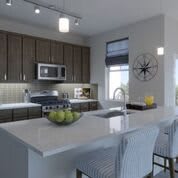 A modern kitchen with an island counter featuring stainless steel appliances and stylish pendant lighting.