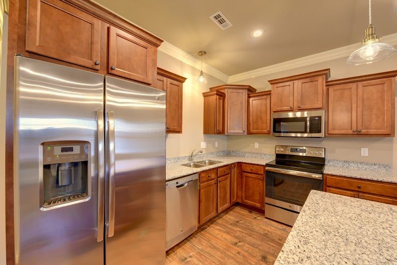 A modern kitchen with wooden cabinets, stainless steel appliances, and granite countertops.