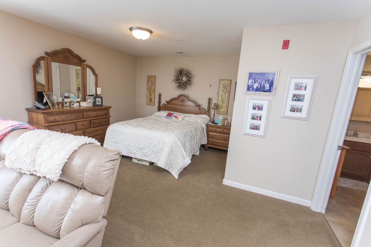A cozy bedroom with a neatly made bed and wooden furniture, including a dresser with a mirror.