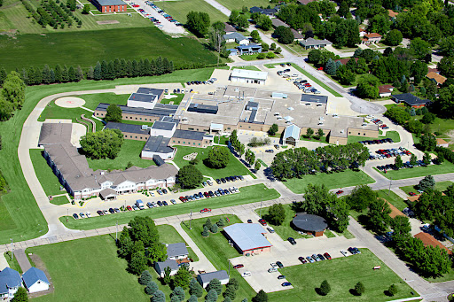 Aerial view of a school campus surrounded by lush greenery and parking areas.