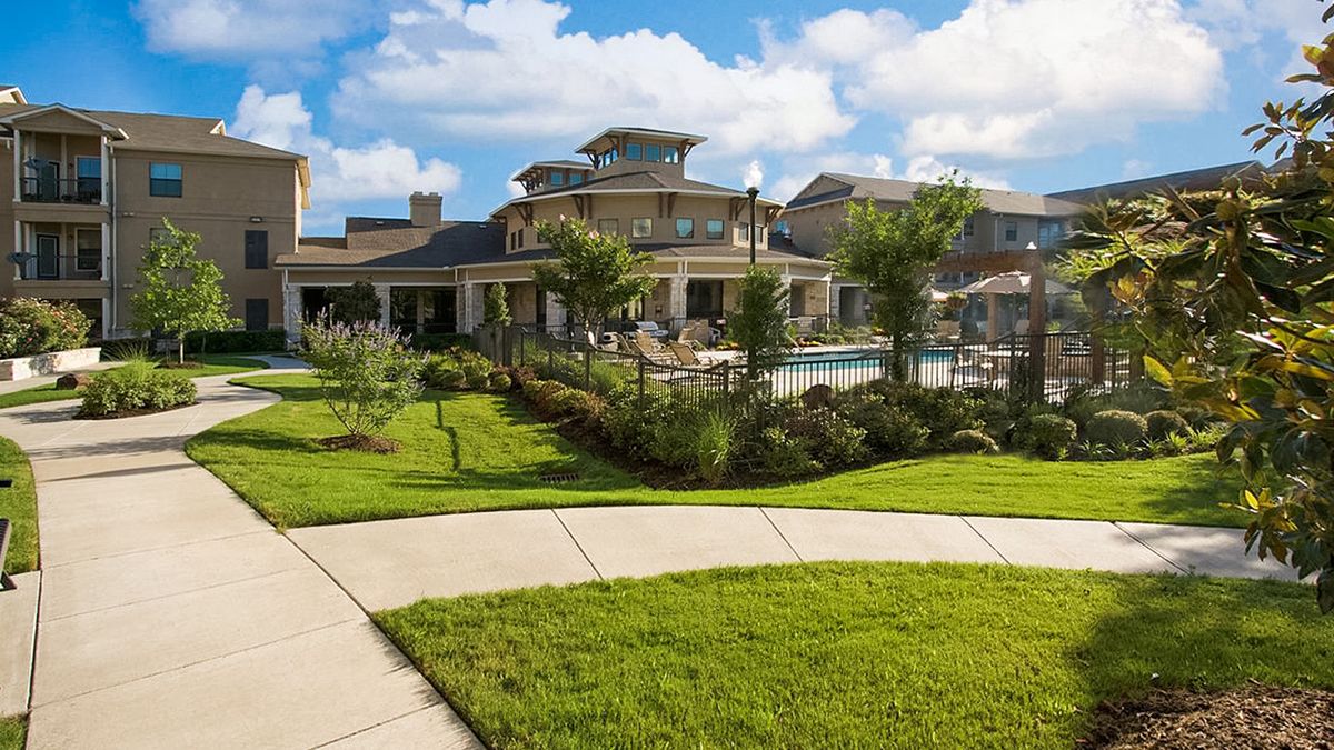 A luxurious residential building with a well-maintained lawn and outdoor pool.