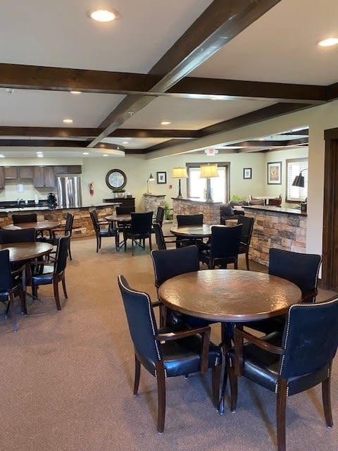 A modern dining area with multiple tables, chairs, and a kitchen in the background.