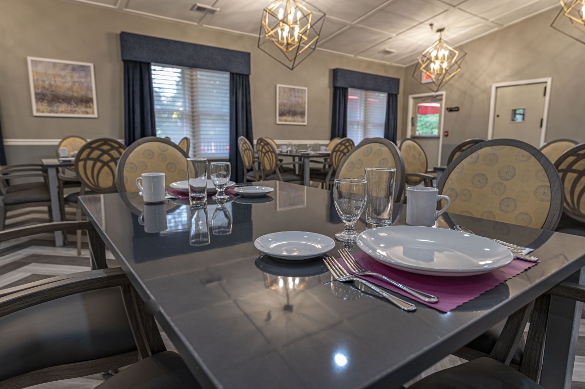 A well-set dining room table with elegant chandeliers overhead.