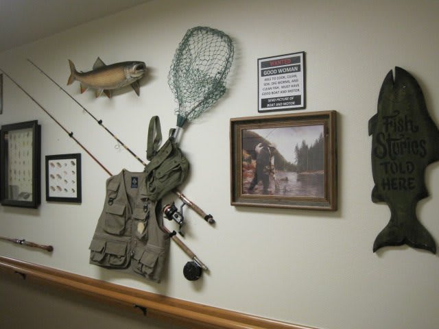 A wall decorated with fishing gear and nature-themed art, including a fishing net, rods, and a fish mount.