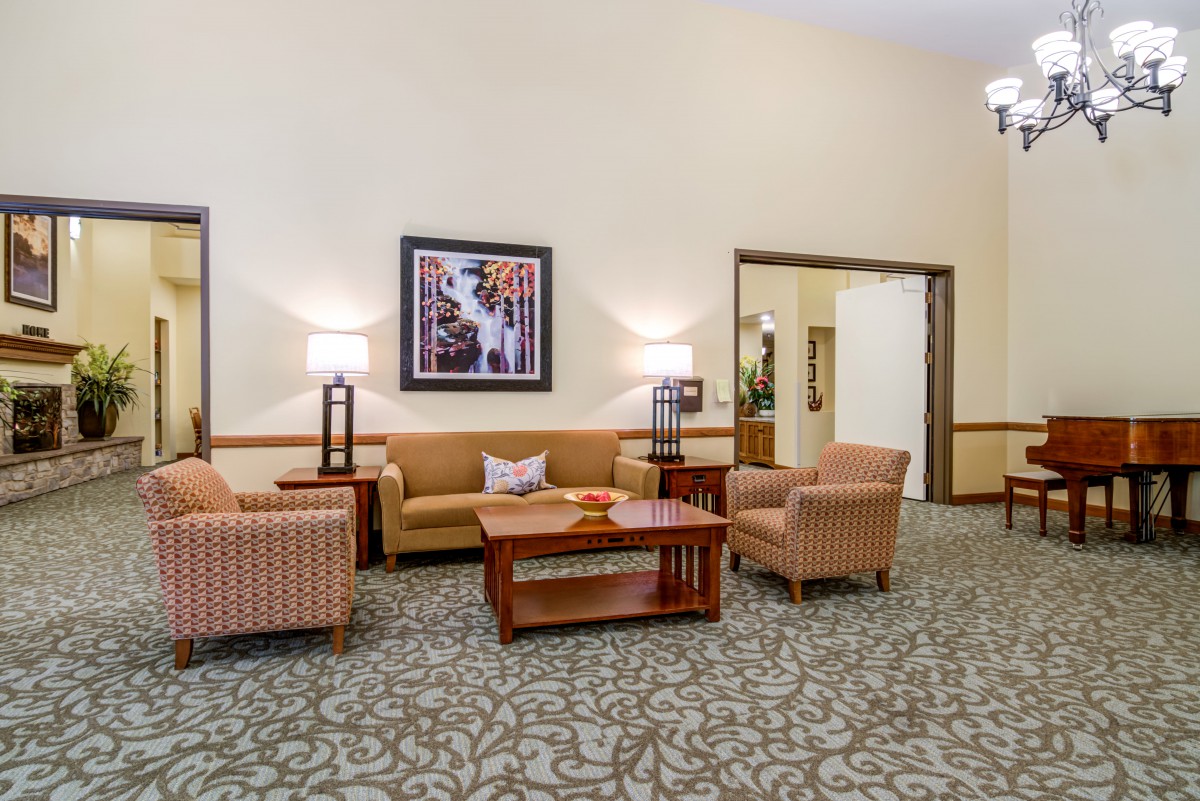 A cozy lobby seating area with sofas, chairs, and a central table, complemented by lamps and artwork on the wall.