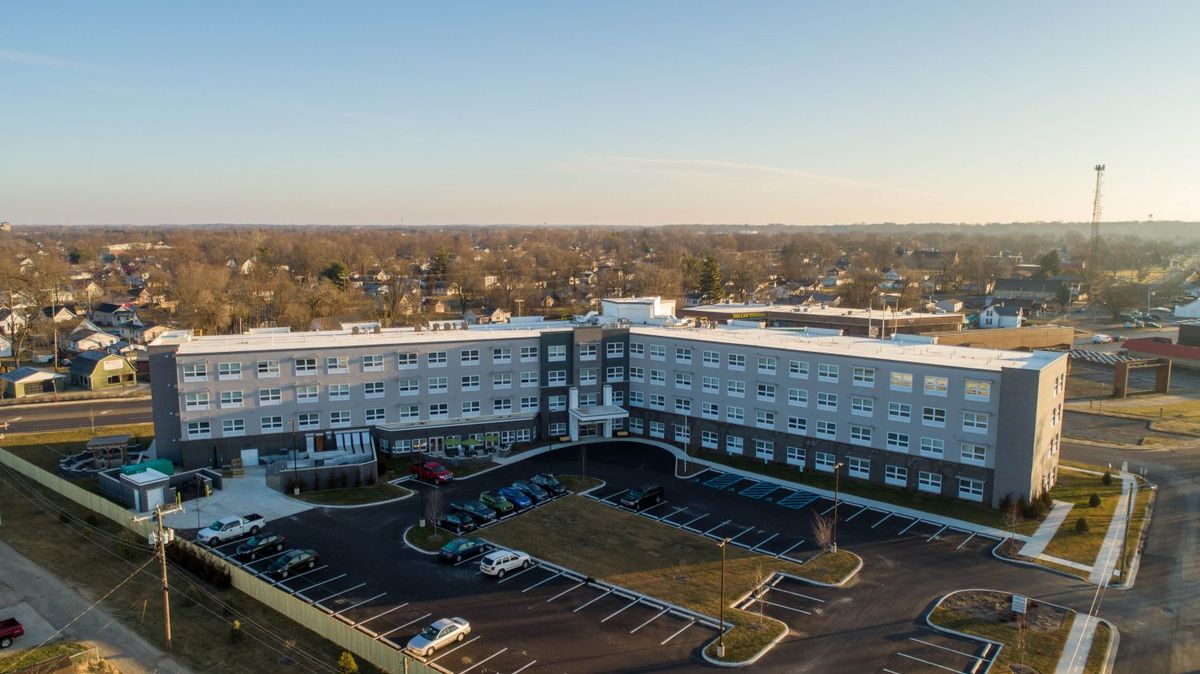 Aerial view of a large building with a surrounding parking lot in a suburban area.