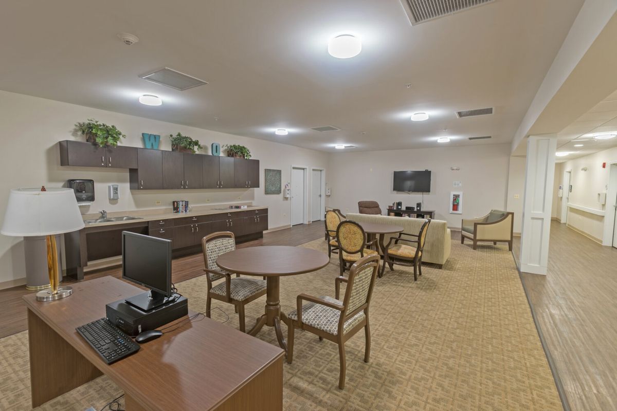 A spacious lounge area with multiple tables and chairs, a television, and a sofa.