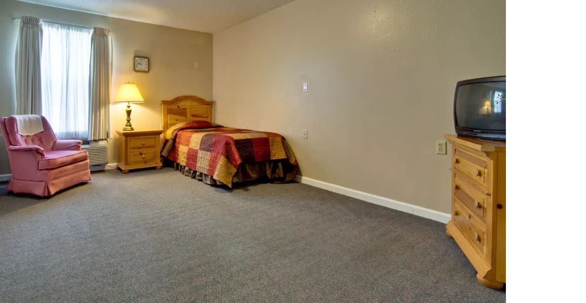 A minimalist bedroom with a single bed, nightstand, and lamp.
