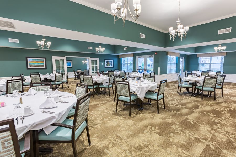 An elegant dining room with neatly arranged tables and chairs, featuring chandeliers and a stylish interior design.