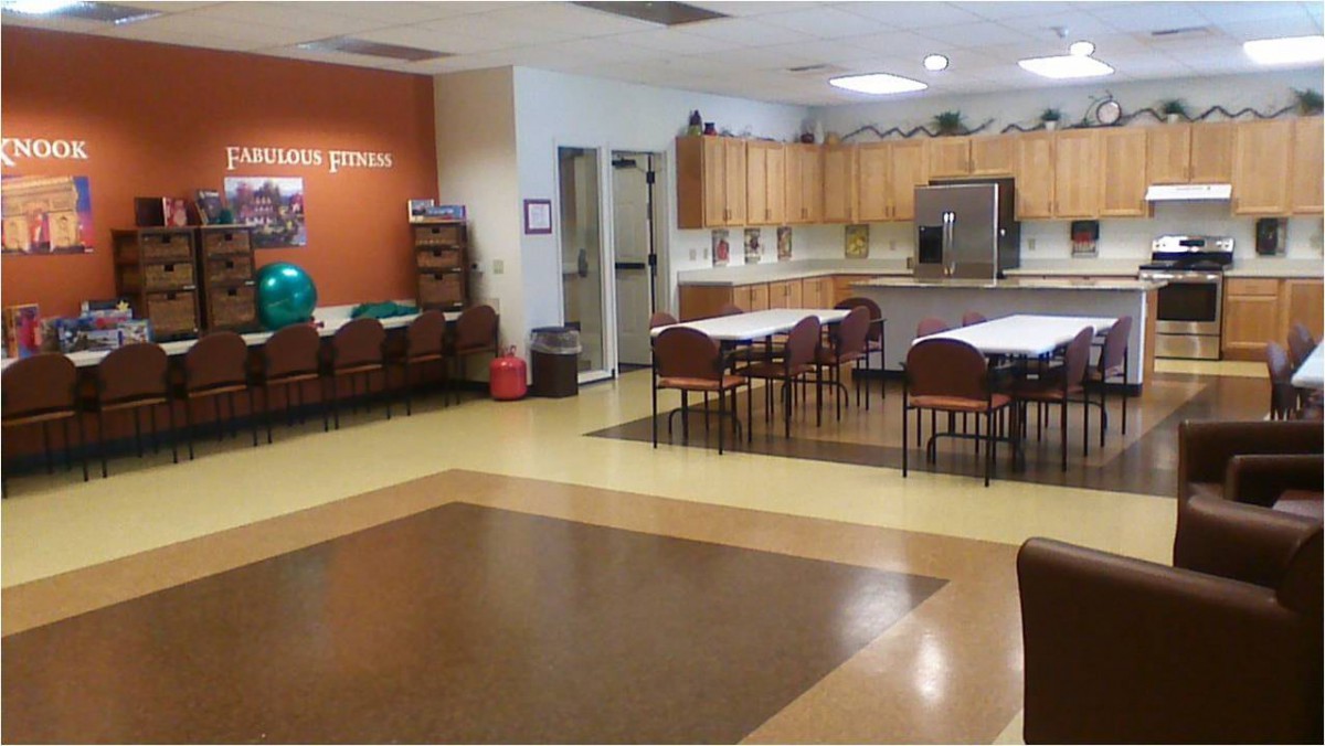 A community kitchen and dining area with tables, chairs, and wooden cabinets.
