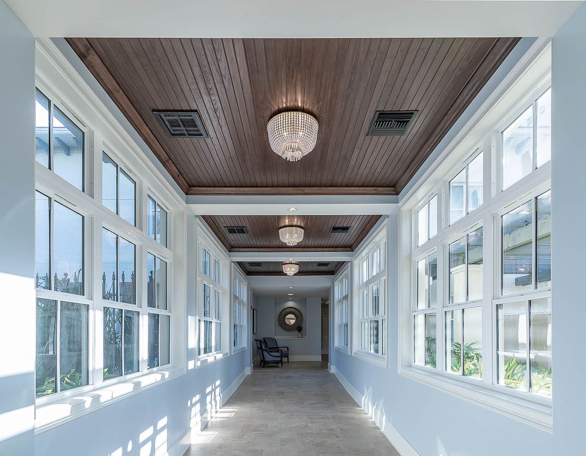 A bright hallway with large windows and elegant ceiling lights.