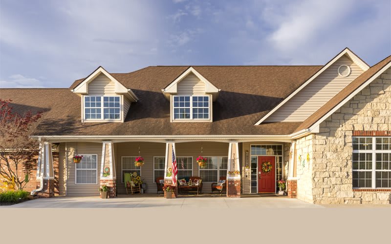 A suburban residential house with a large porch and multiple windows.