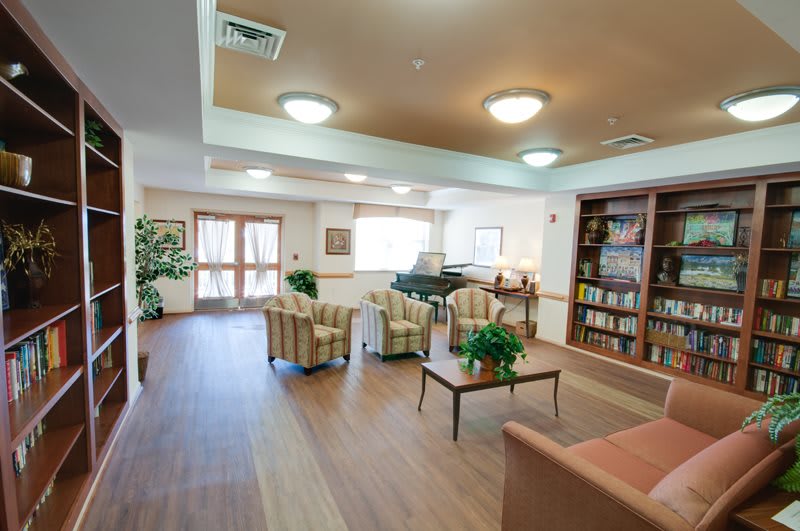 A cozy lounge area with comfortable seating, a piano, and a well-stocked bookshelf.
