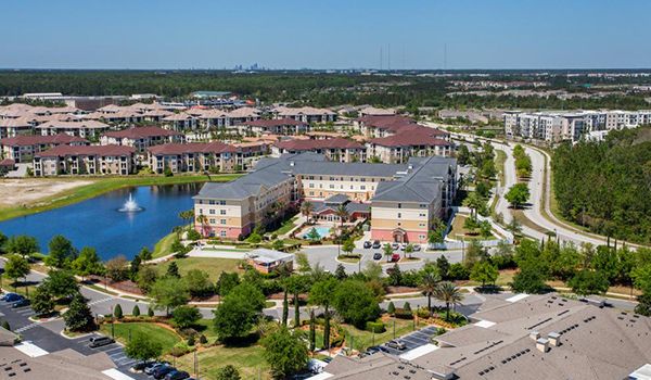 Aerial view of a residential area featuring apartment buildings, a lake, and surrounding greenery.