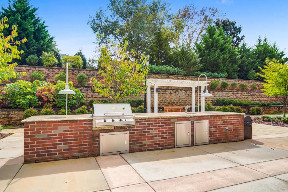 A well-designed outdoor kitchen with a brick grill and a pergola set in a landscaped garden.