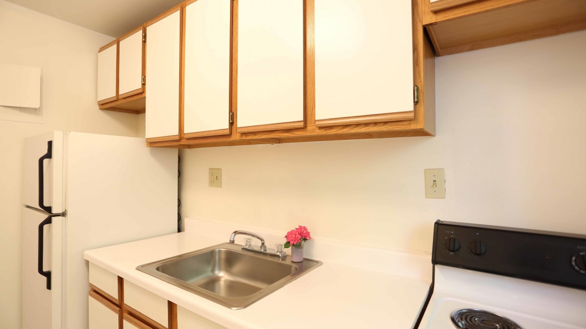 A small kitchen area with a sink, white cabinets, and countertop appliances.
