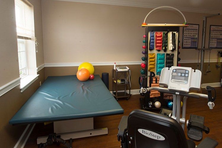 A physical therapy room equipped with a therapy table and various exercise equipment.