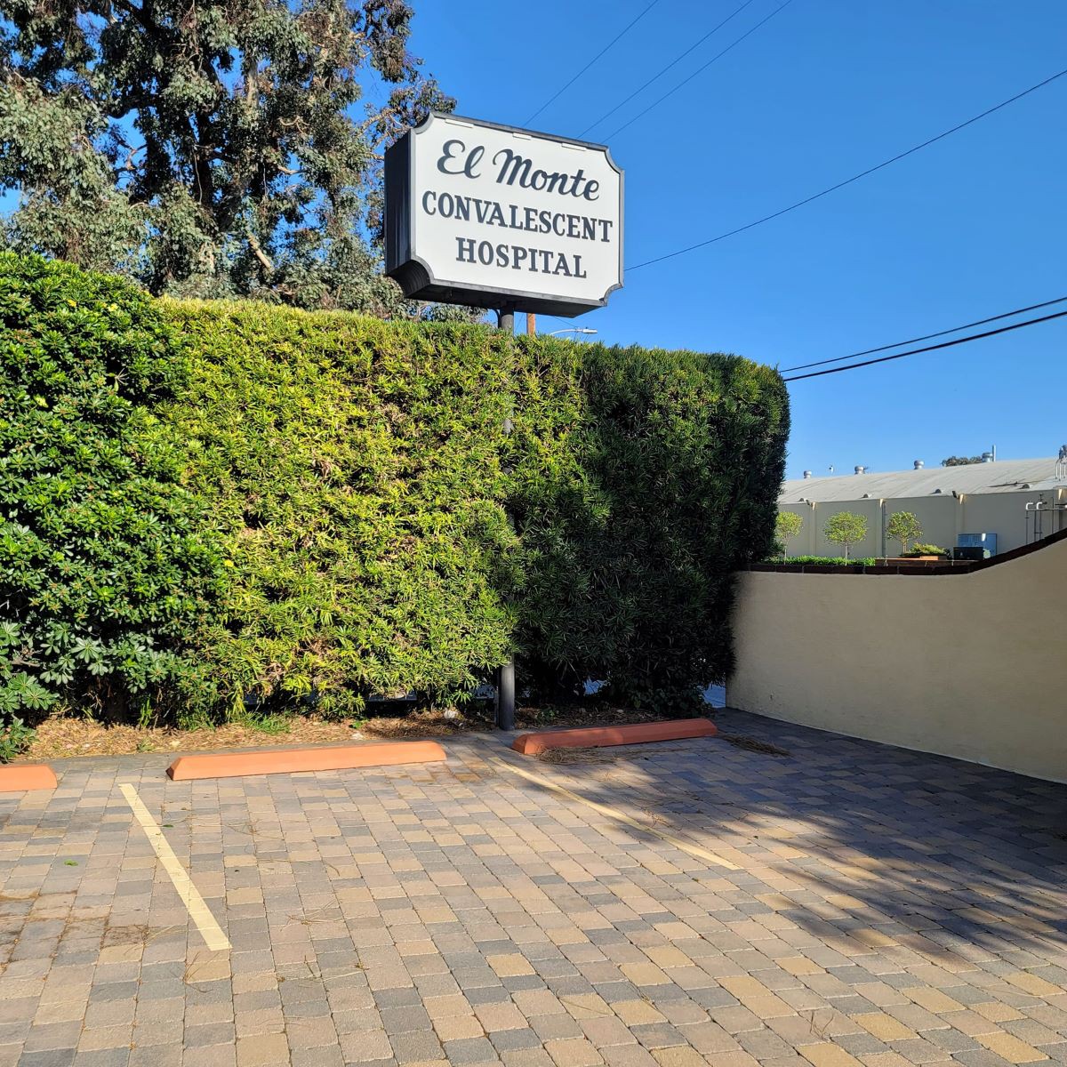 A parking lot in front of a building with a sign that reads 'El Monte Convalescent Hospital'.