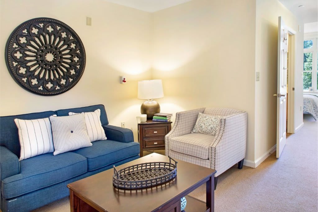 A cozy living room with a blue sofa, an armchair, and decorative elements.