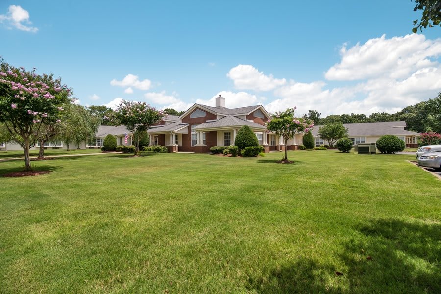 A picturesque suburban house with a large, well-maintained lawn under a clear blue sky.