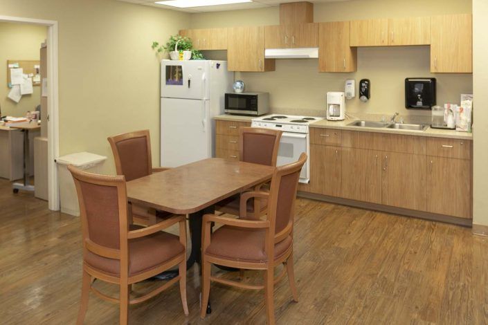 A modern kitchen with wooden cabinets, a dining table, and essential appliances.