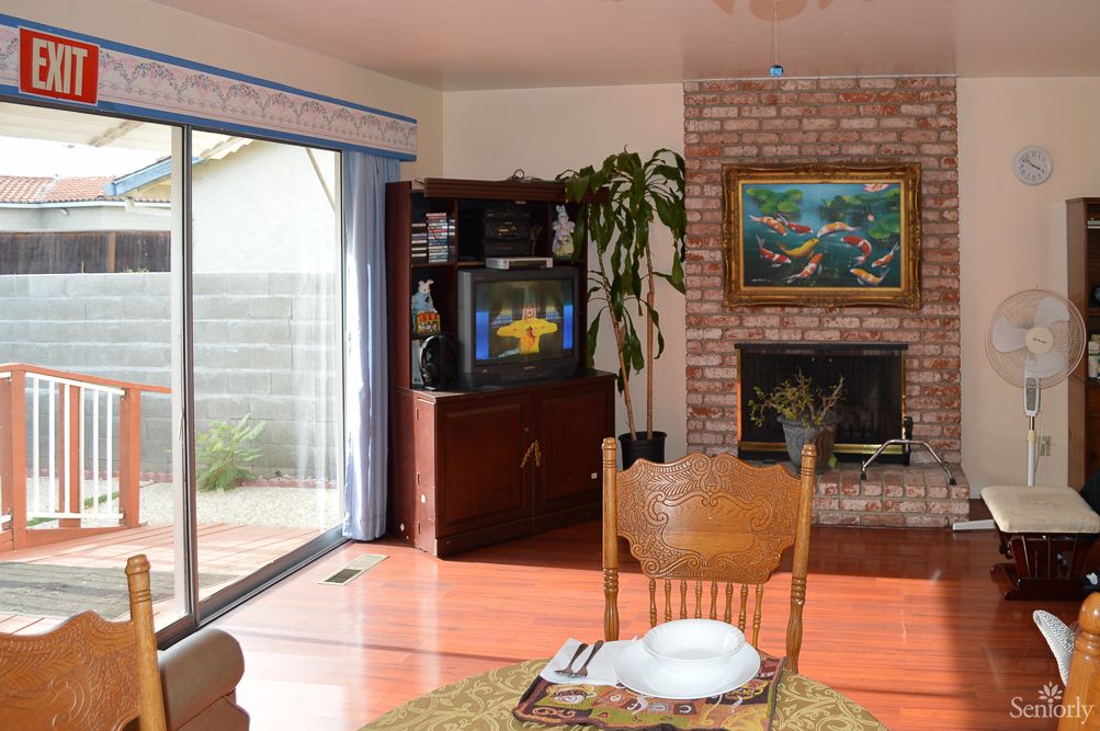Cozy living room with a fireplace and television, featuring wooden furniture and a sliding glass door.